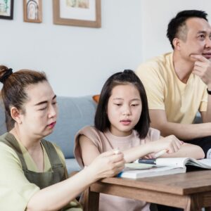 A family helping their daughter with homework in the living room, promoting togetherness.