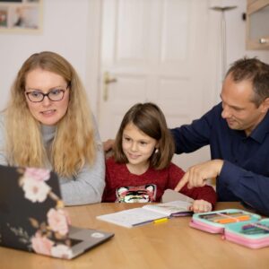 A family is engaged in homeschooling, using technology to learn together in a cozy home setting.