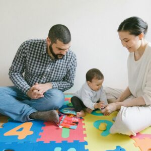 A joyful family playing together on colorful puzzle mat indoors, fostering happy and diverse family moments.