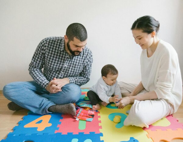 A joyful family playing together on colorful puzzle mat indoors, fostering happy and diverse family moments.