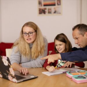 A family learning together with a laptop at home, emphasizing collaboration and education.